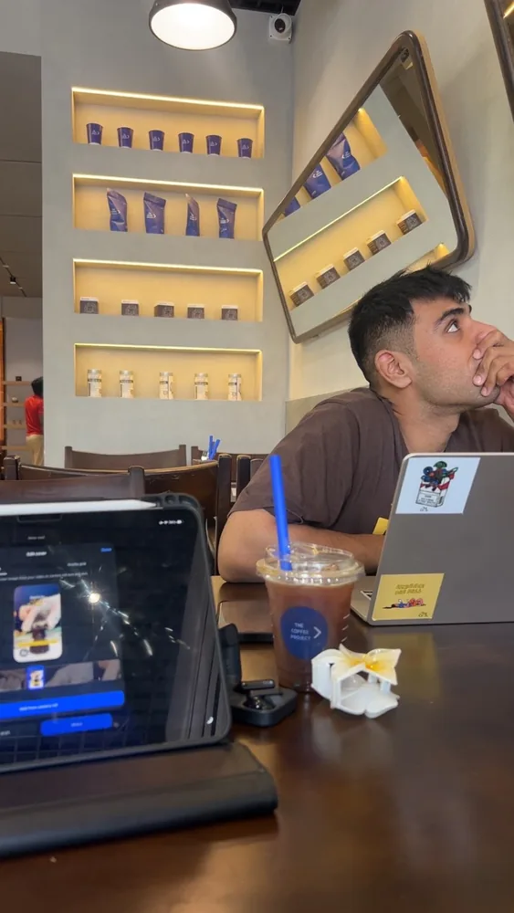Nihal working at a cafe with an iPad and iced coffee